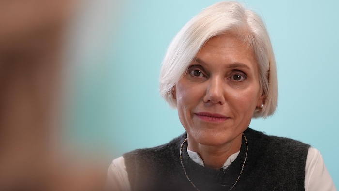 Une femme assise en discussion avec une autre personne.