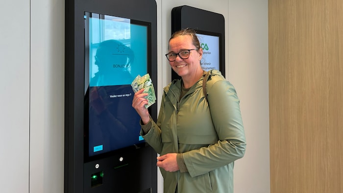  Marie-Josée Racine montre des 20 $ et des 5 $ au Consignaction+.