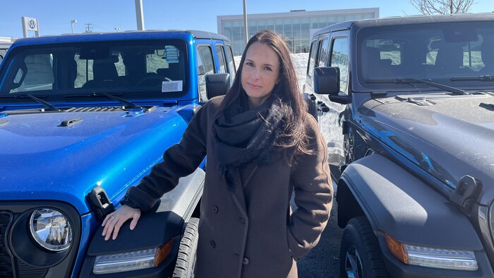 Marie-Lee Michaud pose devant deux véhicules.