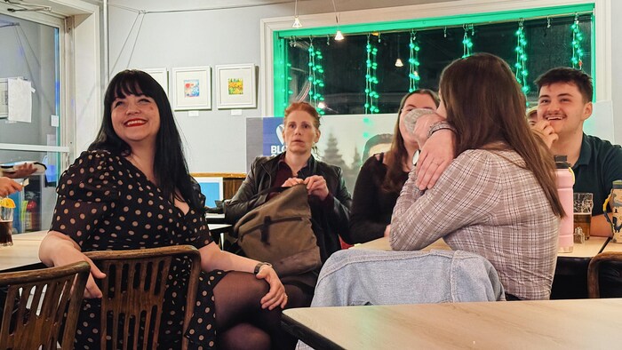 Un groupe de personnes assises regardent au loin en souriant. 