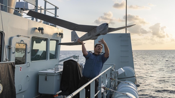 Un marin du NCSM Yellowknife lance un drone d'observation sur la passerelle du navire.