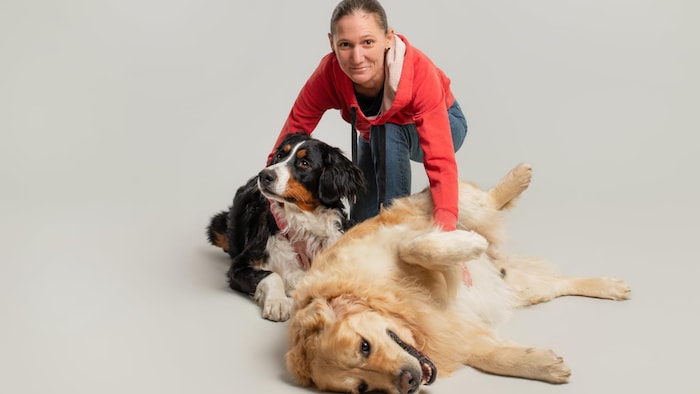 Marina Bourgon tâte deux chiens, l'un couché sur le ventre, l'autre couché sur le côté.