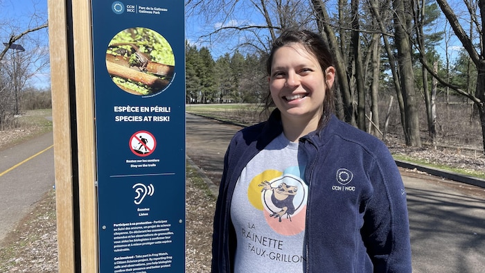 Marina Torreblanca, biologiste pour le parc de la Gatineau et les terrains urbains du Québec à la Commission de la capitale nationale, pose devant un panneau "espèce en péril".