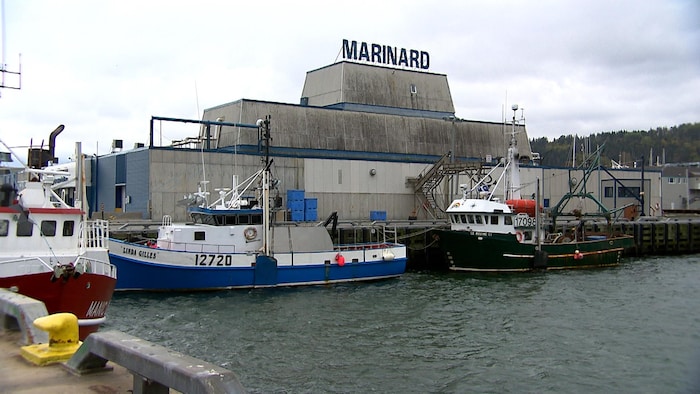 L'extérieur de l'usine de transformation Marinard. Des bateaux se trouvent à quai devant.