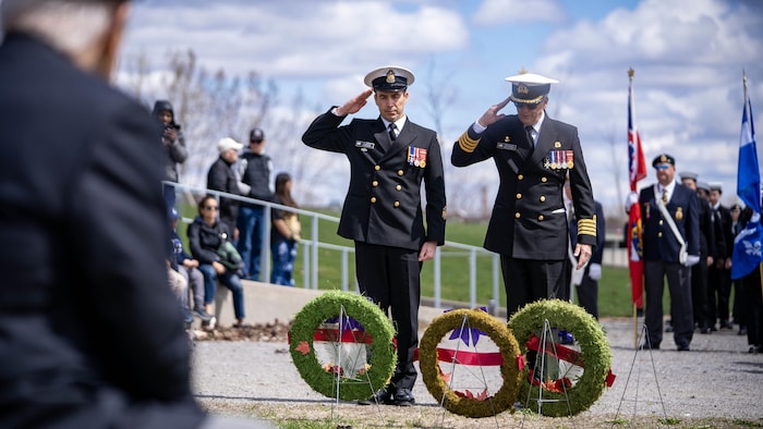 Des membres de la Marine royale canadienne en uniforme devant des couronnes commémoratives. 
