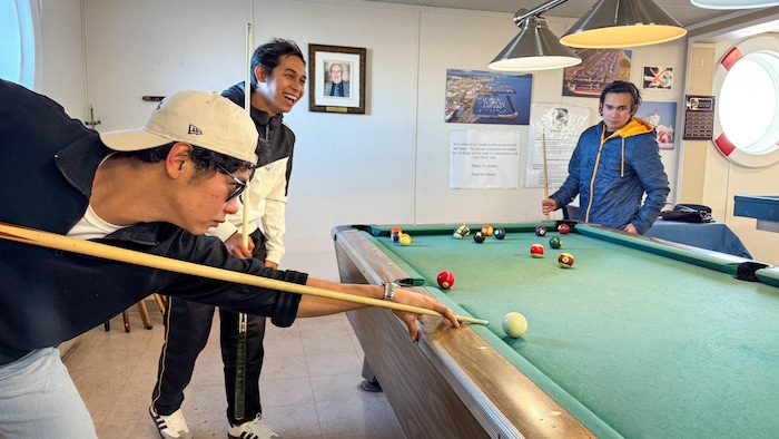 Des hommes jouent au billard.