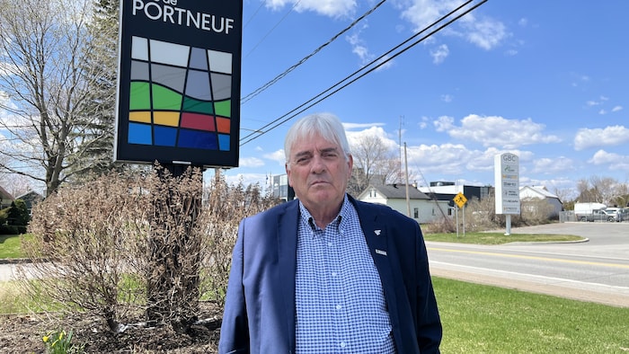 Mario Alain pose à l'extérieur, devant un panneau avec le logo et les mots MRC de Portneuf.
