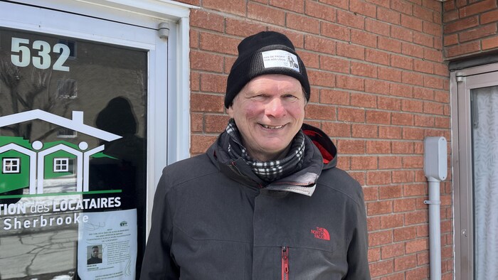 Mario Mercier sourit à la caméra devant la porte d'entrée de l'association.