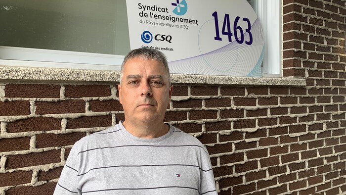 Mario Simard devant un mur de brique.