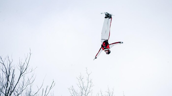 Une skieuse effectue une figure, tête à l'envers.