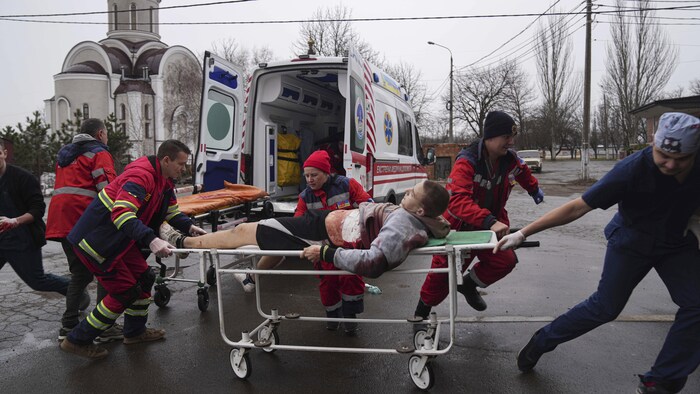 Un homme blessé sur une civière entouré de secouristes.