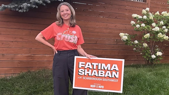 Marit Stiles pose à côté d’une affiche de la candidate du NPD ontarien à l’élection partielle du 3 septembre 2026 dans Scarborough-Sud-Ouest.