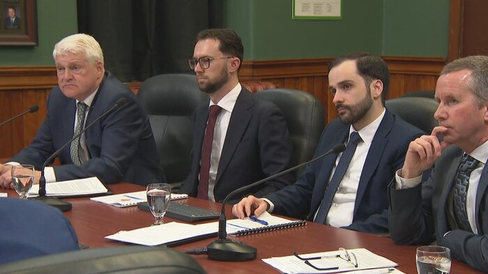 Quatre hommes assis dans une salle. 