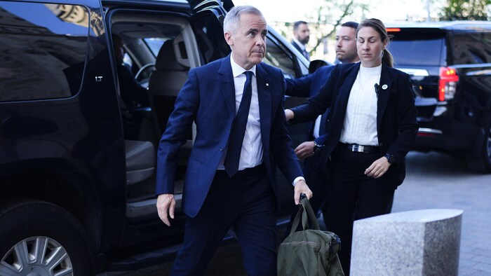 M. Carney sortant d'un véhicule.