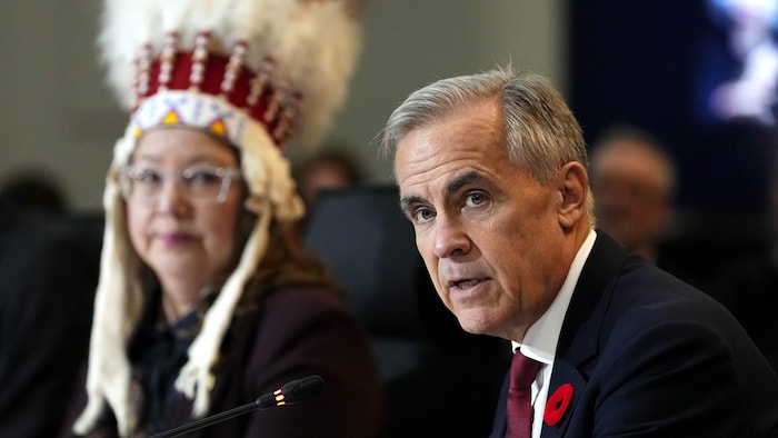 Le Premier ministre Mark Carney prononce un discours sous le regard de Cindy Woodhouse Nepinak, chef nationale de l'Assemblée des Premières Nations, lors d'une réunion entre les Premières Nations et les Premiers ministres à Ottawa, le lundi 26 octobre 2026.