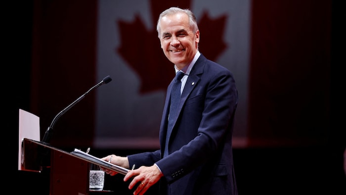 Mark Carney sourit sur une scène.