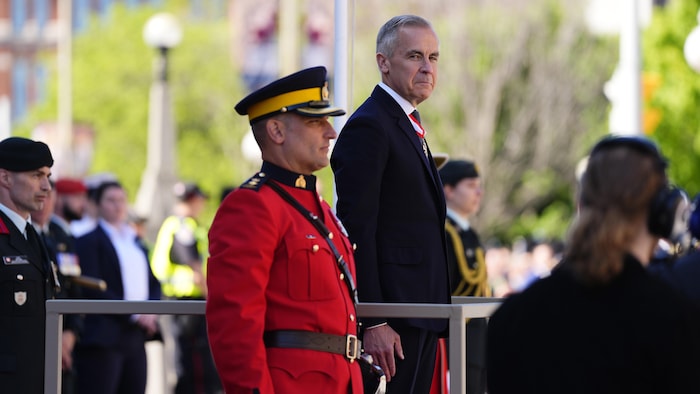 Mark Carney sur une estrade devant une garde d'honneur.