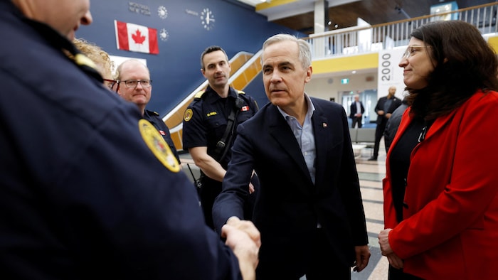 Mark Carney serre la main d'agents.