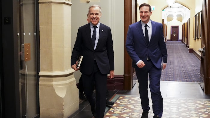 Mark Carney et Marco Mendicino marchent dans les couloirs du parlement.
