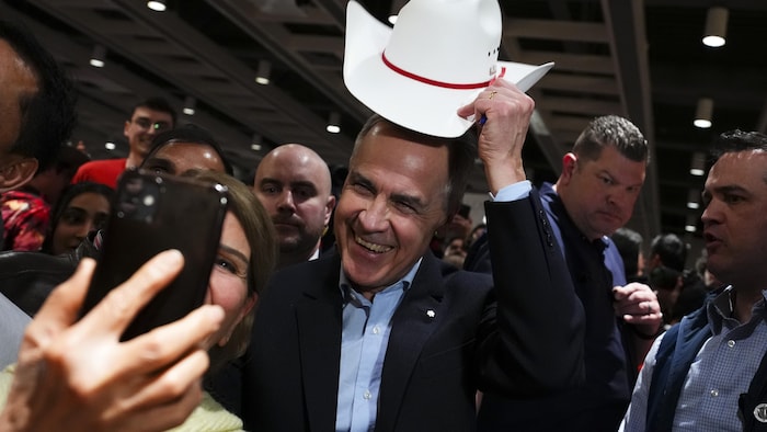 Mark Carney lève lad chapeau de cowboy determination un representation avec une électrice.
