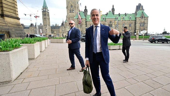Mark Carney parle aux médias devant le parlement.