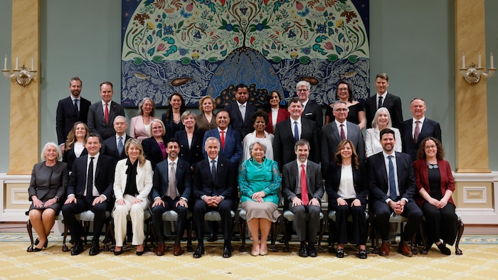 Portrait de famille montrant Mark Carney et Mary Simon assis au centre, entourés par les 28 ministres et secrétaires d'État à Rideau Hall.