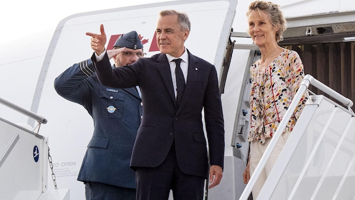 Mark Carney et son épouse s'apprêtent à monter à bord d'un avion.