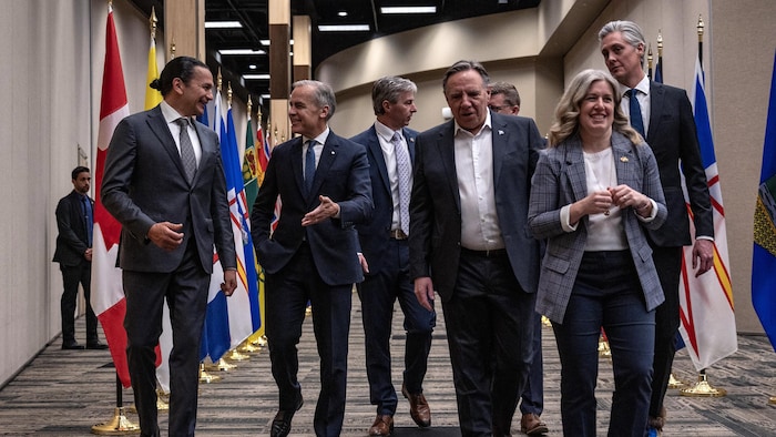 Le premier ministre Mark Carney, marchant aux côtés de Wab Kinew, Susan Holt, et François Legault, entre autres, avant le début de la rencontre à Saskatoon, le 2 juin 2025.
