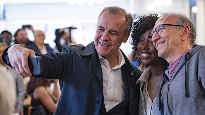 Mark Carney et Tatiana Auguste prennent un égoportrait avec un électeur.
