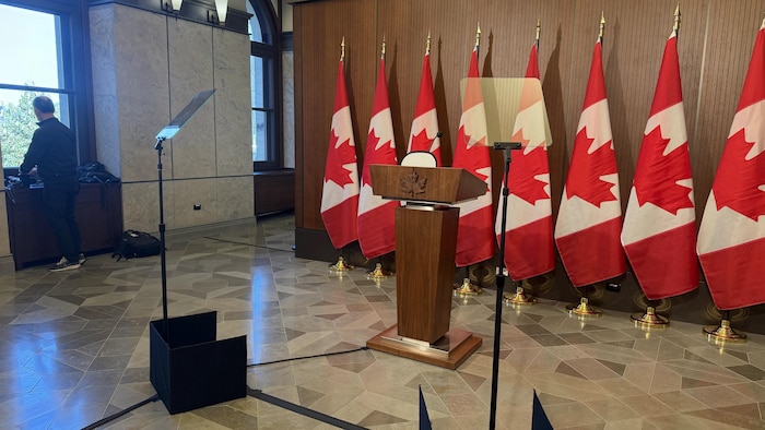 Un lutrin devant des drapeaux canadiens.