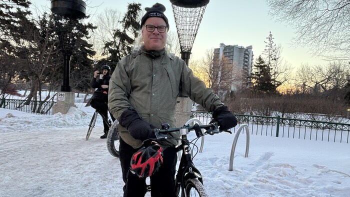 un home debout avec un vélo