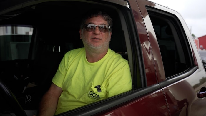 Mark Burer à la fenêtre de sa camionnette rouge.