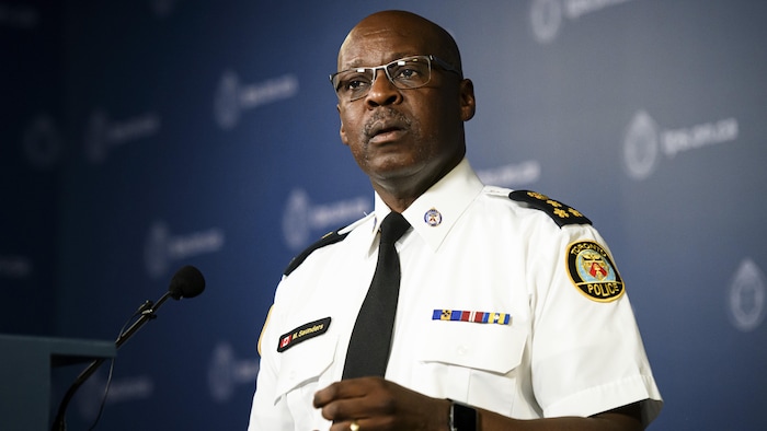 Un homme, habillé en uniforme de police, devant un lutrin. 