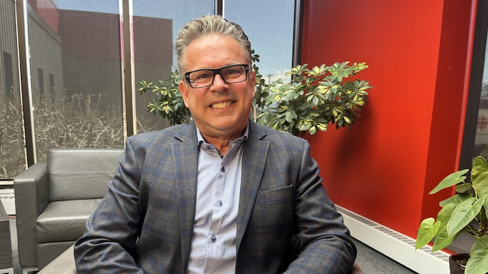 Mark Wilson est assis dans une chaise et regarde la caméra.