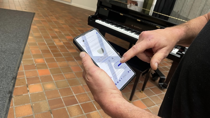 Un homme tient son téléphone entre ses mains. 