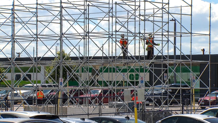 Deux travailleurs dans des échafauds devant la gare Go Unionville.