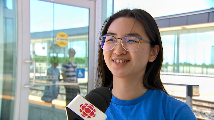Rysisca Yau en entrevue avec un journaliste dans une station de train.