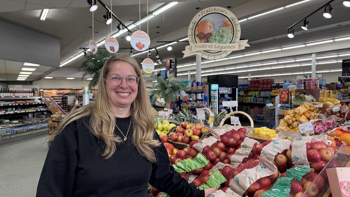 Marlène Landry est entourée de pommes dans une épicerie.