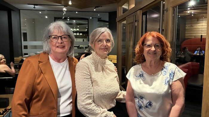 Les trois femmes sourient à la caméra.