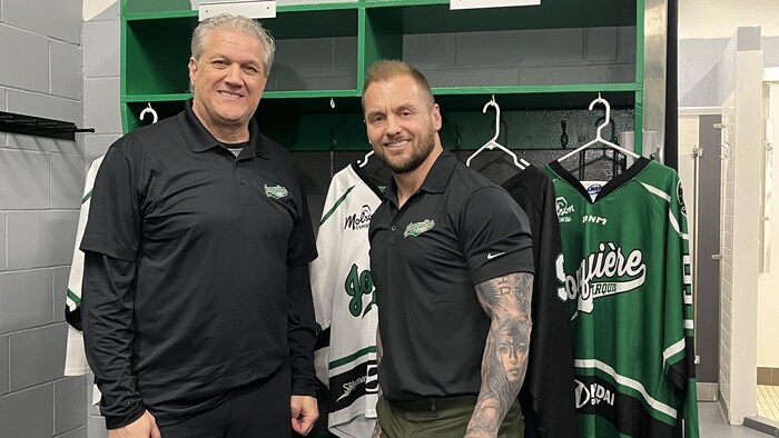 Les deux hommes dans le vestiaire de baseball devant des chandails aux couleurs des Marquis.
