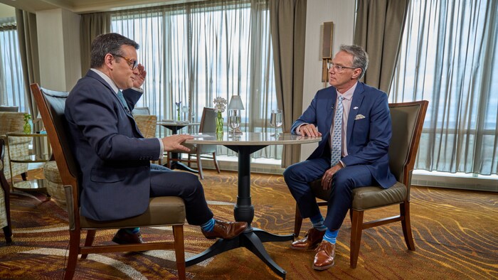 Deux hommes assis face à face avec une table au milieu.