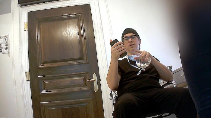 Le médecin porte son uniforme et consulte son téléphone cellulaire.