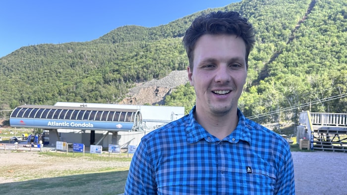 Un homme interviewé devant un centre d'accueil à flanc de montagne.