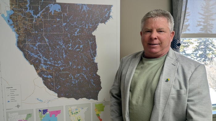 Martin Lefebvre se tient debout à côté d'une carte du Témiscamingue.