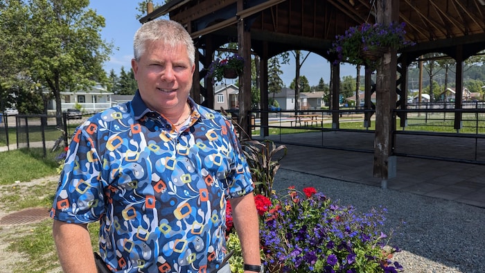 Le maire sourit pour la photo à l'extérieur, devant un pot de fleurs.