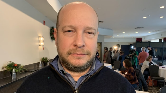 Un homme regarde la caméra.