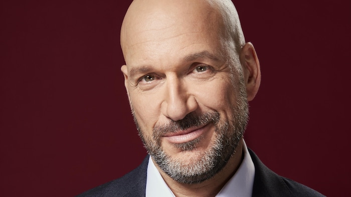 Un homme chauve sourit.