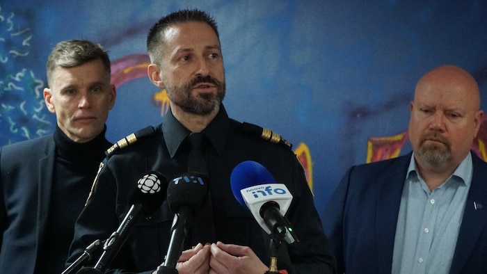 Un homme en uniforme de police en conférence de presse. 