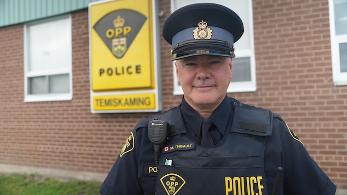 Un policier qui porte son habit devant l'édifice de la police provinciale.