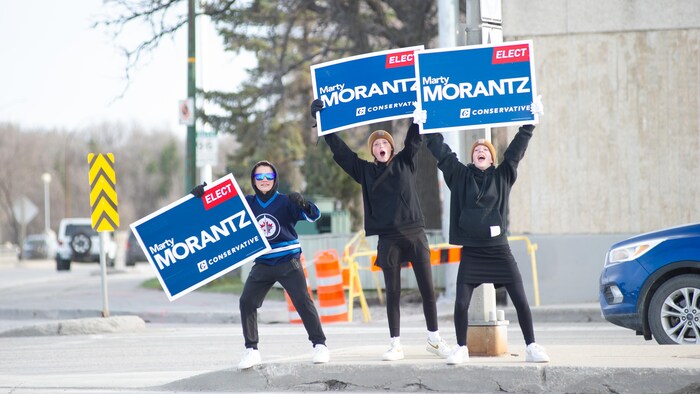 Les partisans du candidat conservateur Marty Morantz font campagne à l'intersection de l'avenue Portage et de la rue Moray avant la fermeture des bureaux de vote au Manitoba le 28 avril 2025. 